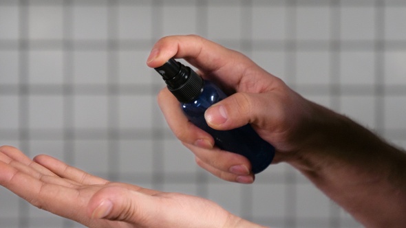 Man dispensing hand sanitizer into hands and sanitizing them. alt