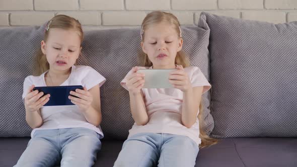 Twins Using Smatphones on Sofa