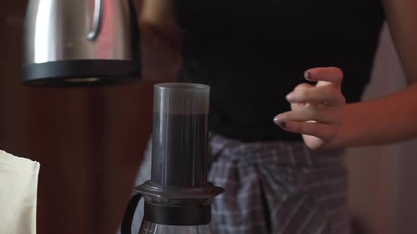 Cafe Worker Pouring Boiling Water From Metal Kettle Into Aeropress to Brew Coffee Close Up in Slow alt