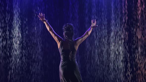 An Attractive Woman in a Wet Dress Performs Elegant Movements with Her Hands in a Dance. A Female alt