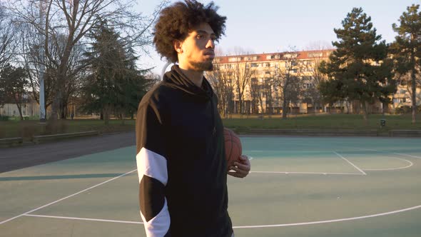 Young man with basketball standing on a basketball field alt