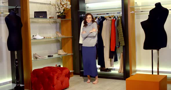 A Dark-haired Slender Woman Is in the Women's Wardrobe of the Fitting Room with Mannequins and alt