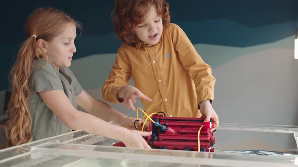 Pair of Kids Putting Plastic Robo Boat into Water alt