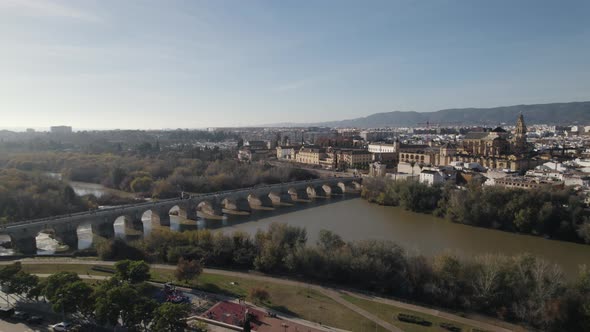 Aerial drone flyback pov of medieval Roman bridge over Guadalquivir river. Cordoba in Spain