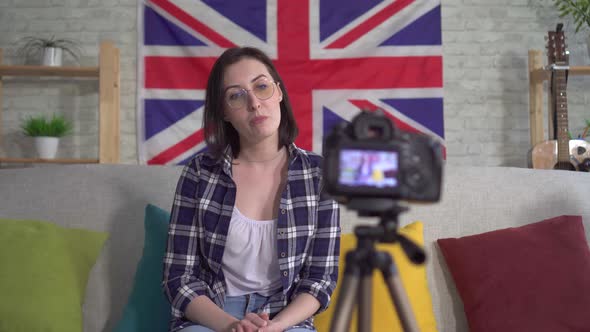 Portrait Young Woman Blogger in Shirt on the Background Flag of Great Britain Recording Video alt