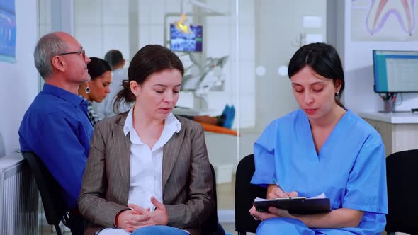Nurse Taking Notes on Clipboard About Patient Dental Problems alt