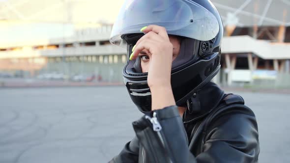 Woman in Black Helmet Looking at Camera, Sitting on Black Sporty Motorcycle alt