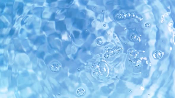 Top view slow motion of drop falling into the water surface and diverging circles on white backgroun alt