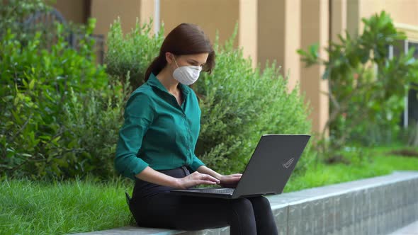 Office Girl in a Medical Mask with a Laptop