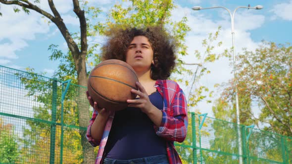 A Young Teenage Girl with an African Hairstyle Throws a Basketball Ball Into the Basket. alt