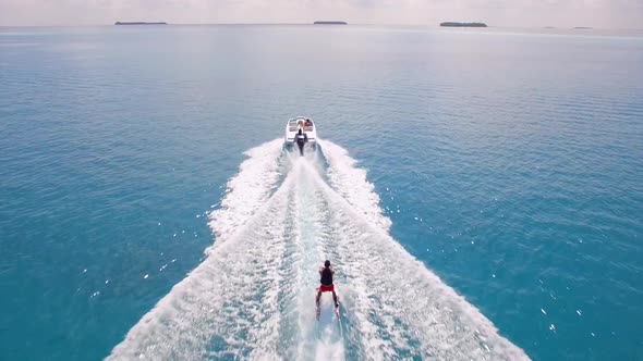 Aerial drone view of a man water skiing near a tropical island alt
