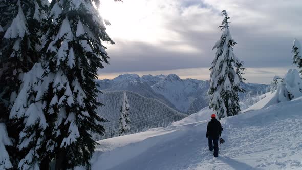 Snowboarder Hiking Mountain Ridge Slow Motion Backcountry Aerial Reveal alt