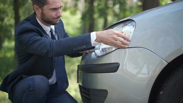Portrait of Young Handsome Male Driver Pushing Car Headlight Fixing Damage alt