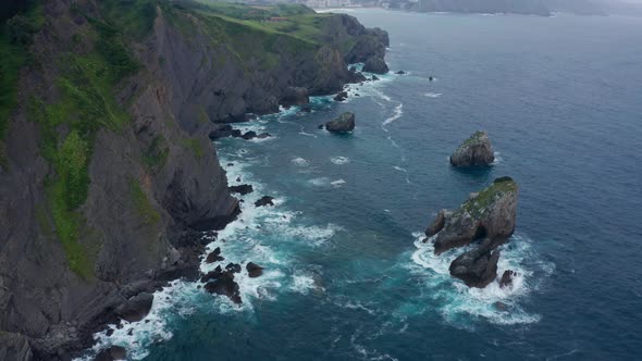 Mossy cliffs near foamy ocean in daylight alt