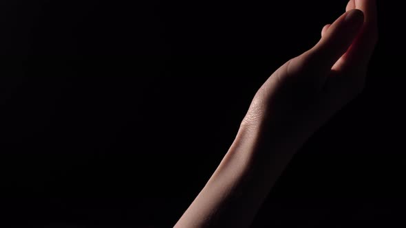 Gentle female hands on black background alt