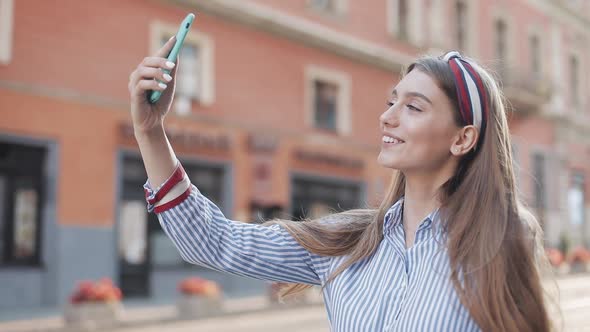 Young Beautiful Caucasian Girl with Brown Hair and Headband on It Using Her Smartphone Making Video alt