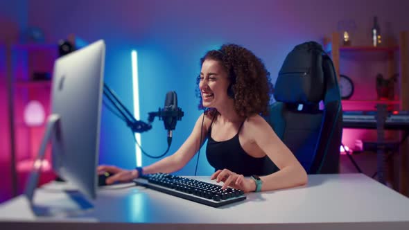 Young Woman Wearing Headphones Playing Computer Game Neon Fashion Room Winner alt