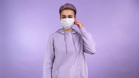 Modern Young Woman Taking Off Medical Face Mask Isolated Indoors alt