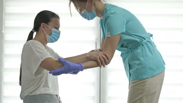 Doctor or Nurse is Helping an Female Patient to Get to Her Feet