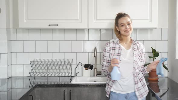 Portrait of Happy Housekeeper Enjoys the Cleaning Process Dancing in Kitchen with Detergents in Her