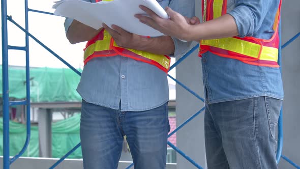 Young Asian engineers and caucasian engineer colleagues at site inspector and discuss together alt