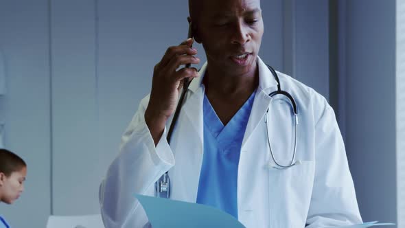 Front view of African American male doctor talking on mobile phone in hospital 4k alt