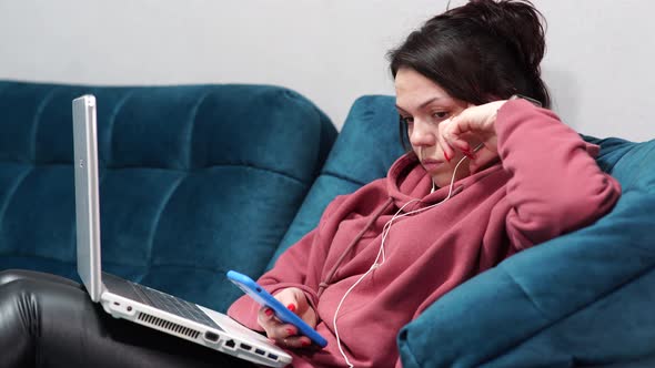 Girl Sitting on Sofa with Headphones and Laptop