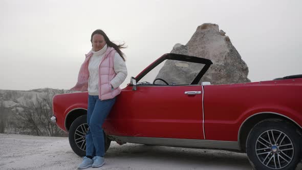 Woman is Standing Near Retro Cabriolet Red Car Among Rocks in Her Road Trip