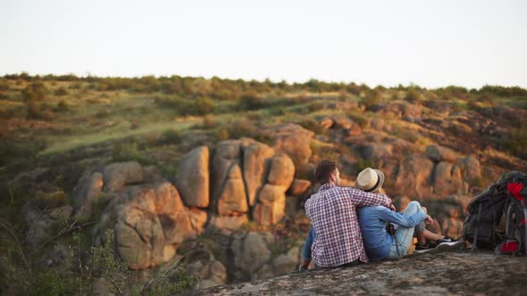Two Young Lovers Sitting on Rock in Prairie Talking Smiling alt