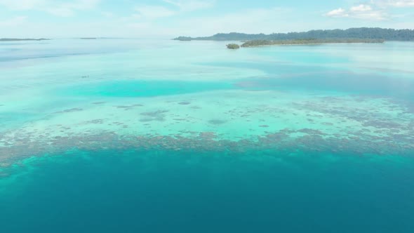 Aerial: flying over coral reef tropical islands caribbean sea turquoise blue water, Indonesia alt