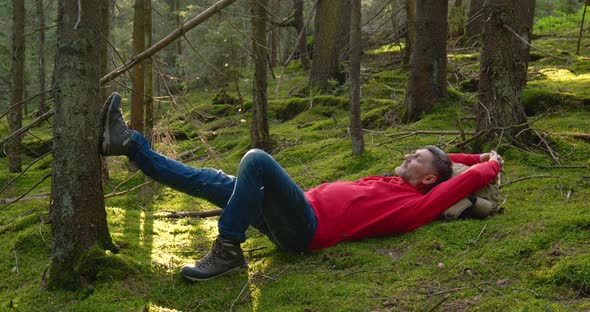 Tourist Guy Resting on Moss in a Beautiful Forest alt
