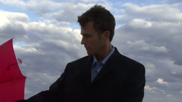 Cu of a male opening an umbrella on a beach and checking if it is raining alt