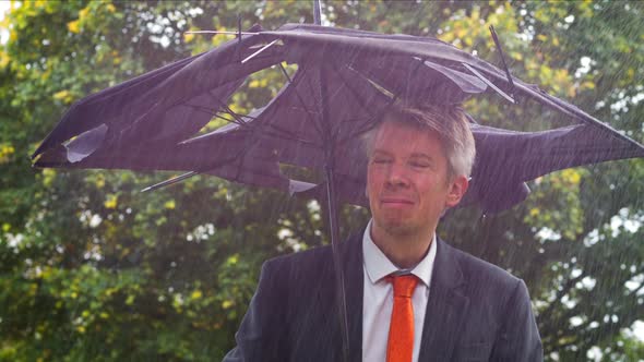 Businessman Sheltering Underneath a Broken Umbrella in the Rain