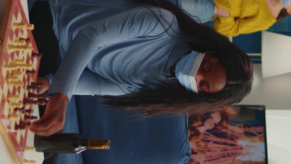 Vertical Video Diverse Friends Clinking Bottles of Beer Playing Chess at Home alt