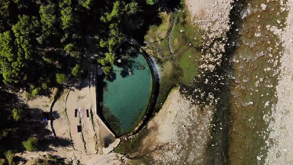 Video From a Drone Flying Up and Sticking Looking Down Above a Pool with a Girl Swiming