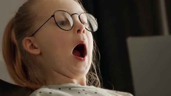 Little child clever kid girl reading a book in glasses after school and amazed alt