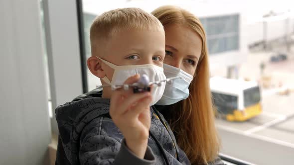 A Mother with a Son with Masks at the Airport Boy is Playing with a Airplane alt