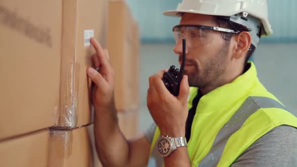 Professional Cargo Worker Talks on Portable Radio to Contact Another Worker alt