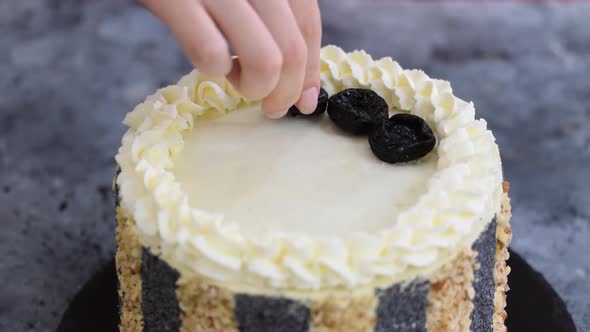 Female Hands Decorate the Top of the Cake with Prunes