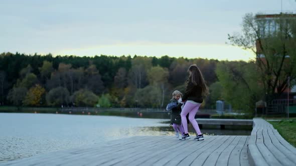 Happy Mom Walks with Her Daughter in the Autumn Park alt