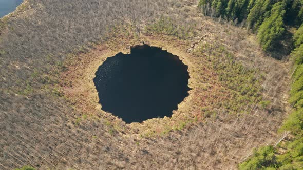 AERIAL: Rotating Shot of Round Deep Blue Lake in Forest