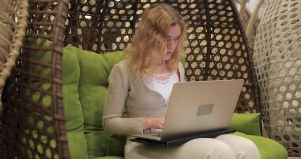 Woman Working By Laptop Sitting in a Cocoon Chair alt