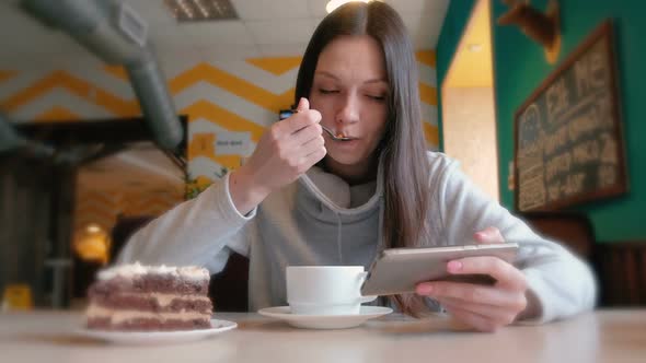 Young Woman Eats a Piece of Cake with a Spoon
