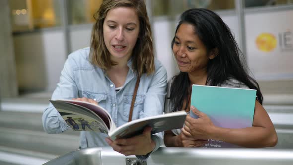 Women looking at book together alt