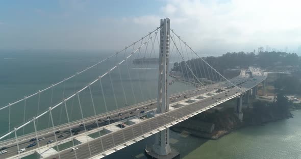 Aerial shot of vehicles moving on San Francisco–Oakland Bay Bridge with city in background alt