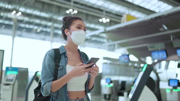 young attractive asian female traveller wearing face mask hand use smartphone