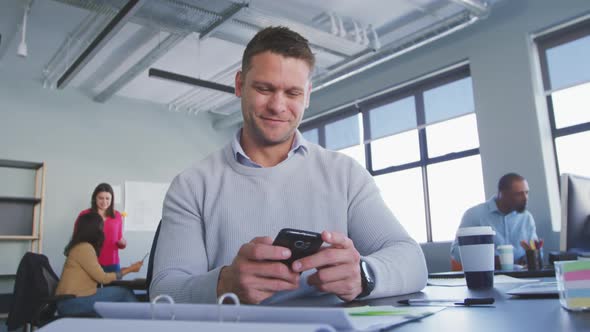 Businessman using smartphone in modern office alt