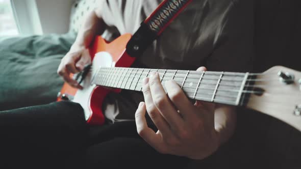 Close Up of Young Man Playing on Red Electric Guitar Funk or Blues Next To Window. Slow Motion