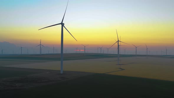 Eolian turbine farm at sunrise. Wind turbine silhouette. Wind field turbines alt