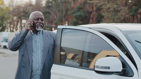 Elderly African American Man Talking on Mobile Phone Walks Up to Car Sits Down in Front Passenger alt